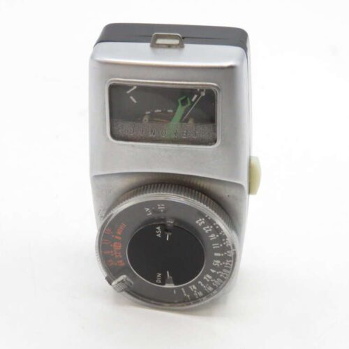 A vintage manual light meter with a metallic body, featuring a display window showing a needle and gauge, and a large adjustable dial with ASA and DIN settings.