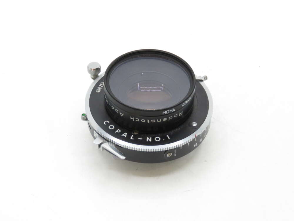 IMG_2244 A Rodenstock Apo-Ronar 150mm camera lens mounted on a Copal-No.1 shutter, featuring a silver and black finish with visible dials and settings.