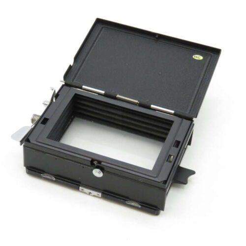 A black photographic film holder with an open top, showing its internal compartment and metal clasps on the sides.