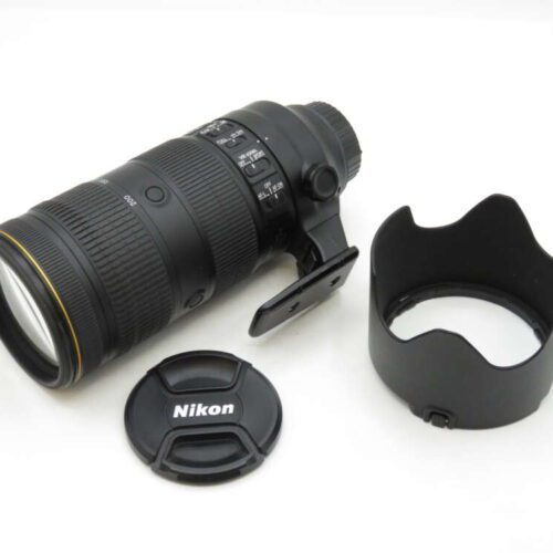 Nikon camera lens with an attached tripod collar, a detached lens hood, and a lens cap displaying the Nikon logo.