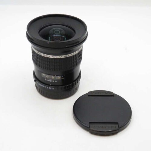 A Pentax-F 645 33-55mm camera lens with a black lens cap placed beside it on a white surface.