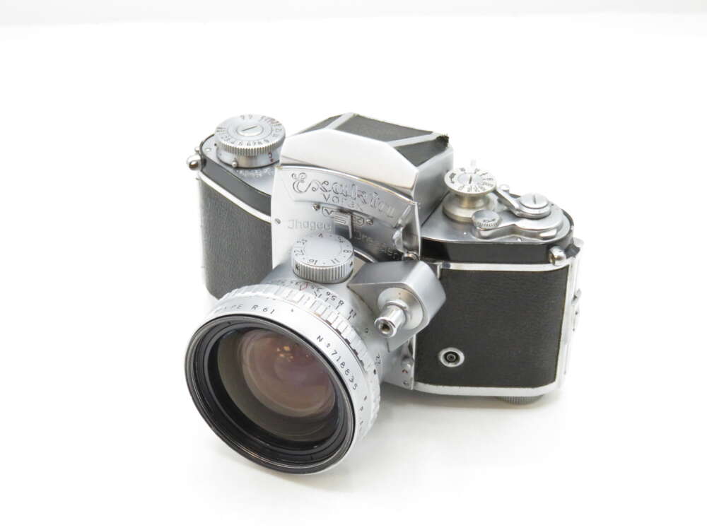 IMG_2317 A vintage Exakta Varex IIa camera with a large lens, featuring a classic silver and black design, placed on a white background.