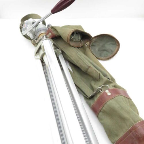 A metallic tripod with a red lever handle, accompanied by a green and brown canvas carrying case, placed on a white background.