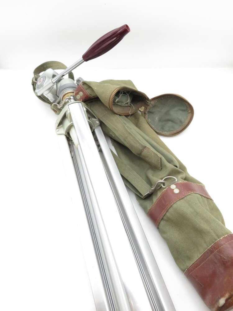 IMG_2354 A metallic tripod with a red lever handle, accompanied by a green and brown canvas carrying case, placed on a white background.