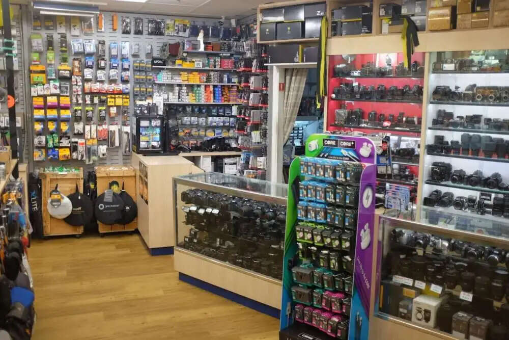 A camera shop interior with display cases filled with camera equipment and accessories, and shelves stocked with various products.