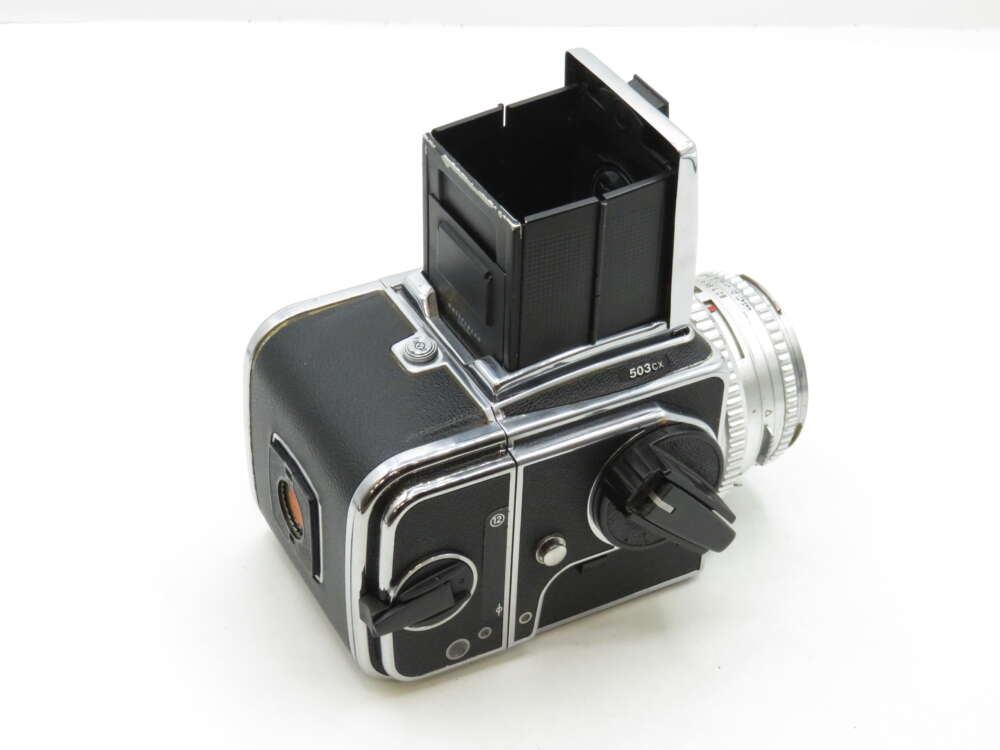 A vintage black and silver medium format camera with a pop-up viewfinder, featuring multiple dials and a silver lens.