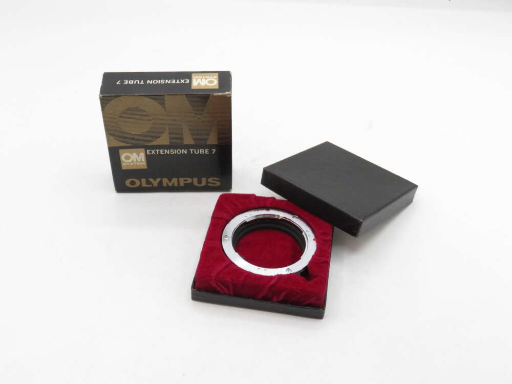 IMG_3063 An Olympus extension tube 7, placed in a red-lined open box, with its packaging beside it.