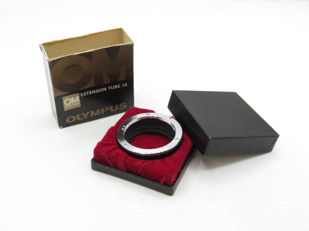 Olympus extension tube 14 displayed on a red velvet pad, next to its box and black lid.