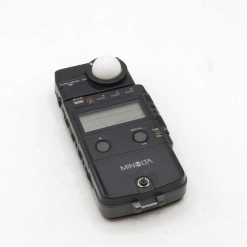 A black Minolta light meter with a white dome and digital display on a white background.