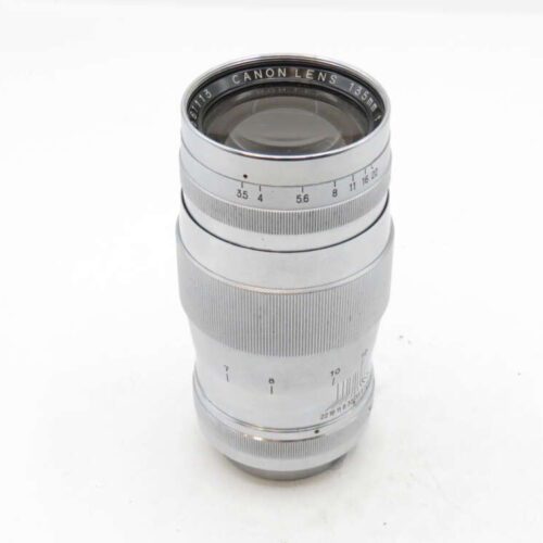 A silver camera lens with a focus dial and aperture settings engraved on the side.