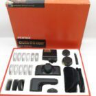 Pentax auto 110 super SLR camera set with accessories, including lenses and flash, in an open red box.