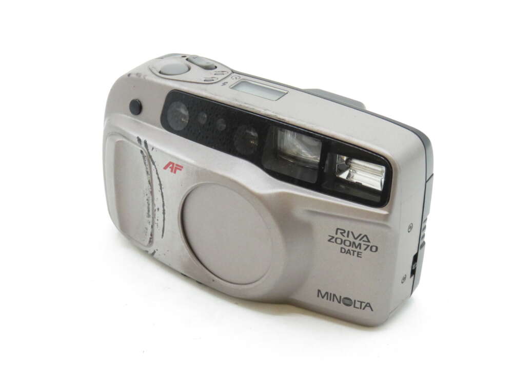 IMG_3240 A silver Minolta Riva Zoom 70 Date camera featuring a lens cover and flash.