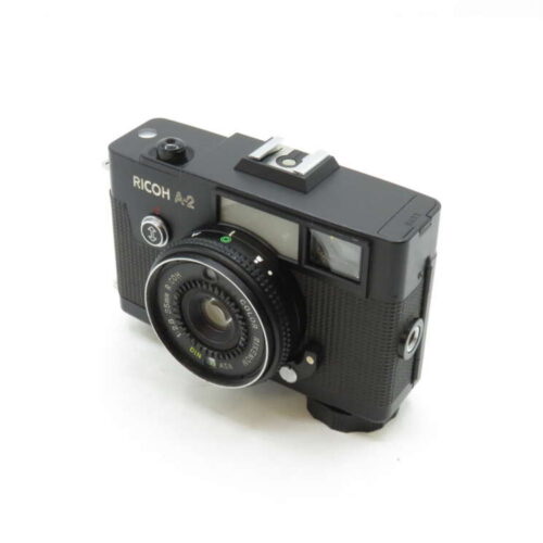 A Ricoh A-2 vintage camera with a textured black body and a prominent lens on a white background.