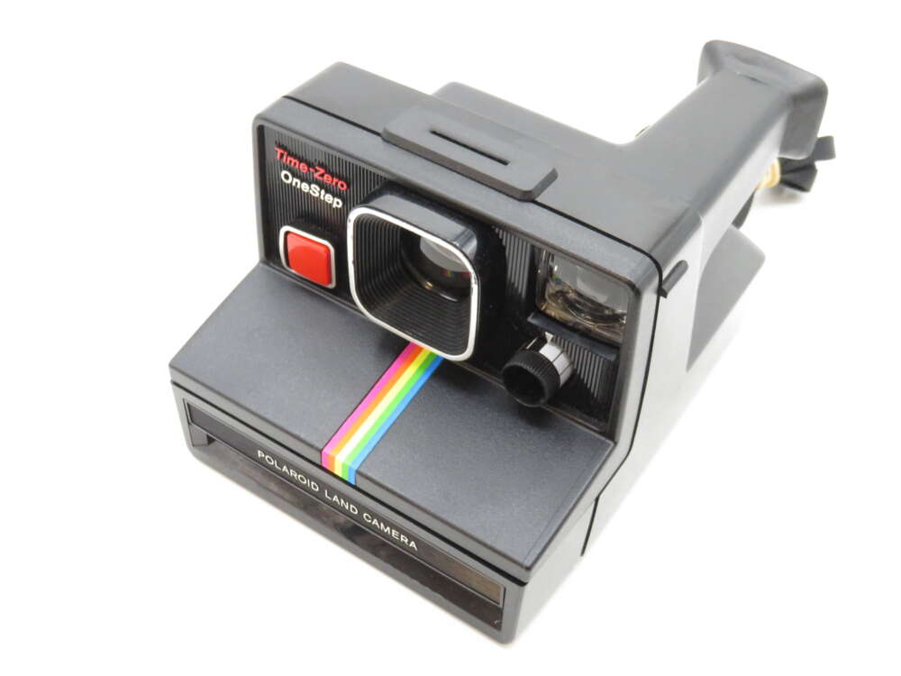 IMG_3376 A vintage Polaroid Land Camera with a rainbow stripe and visible "Time-Zero OneStep" text.