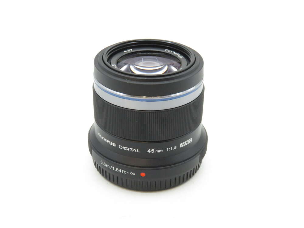IMG_3456 A black Olympus 45mm f/1.8 camera lens with white and silver details, shown on a white background.
