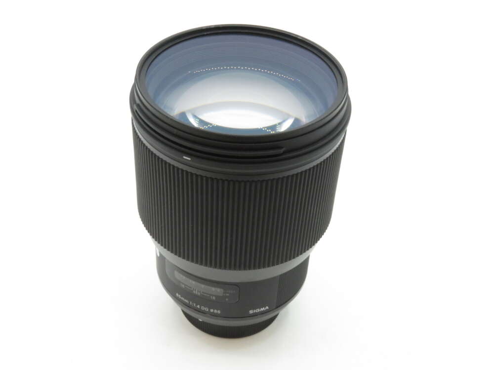 IMG_3467 A black Sigma camera lens with a ribbed focus ring and glass elements visible at the front.