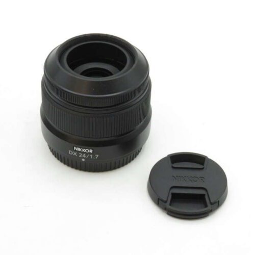 A Nikkor DX 24 f/1.7 camera lens with its detached lens cap beside it.