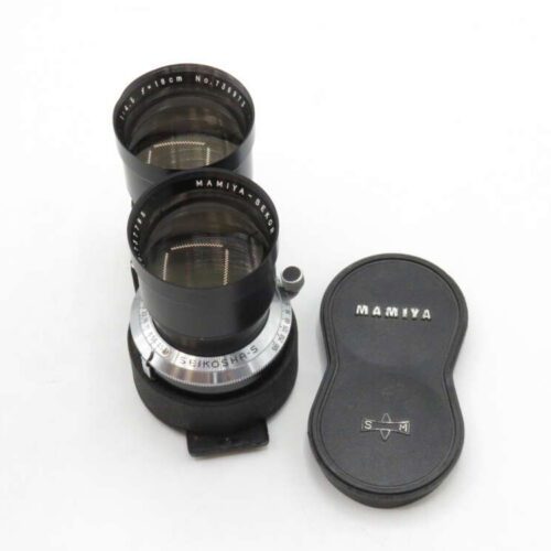 Dual-lens Mamiya camera lens set with a lens cap beside it on a white background.