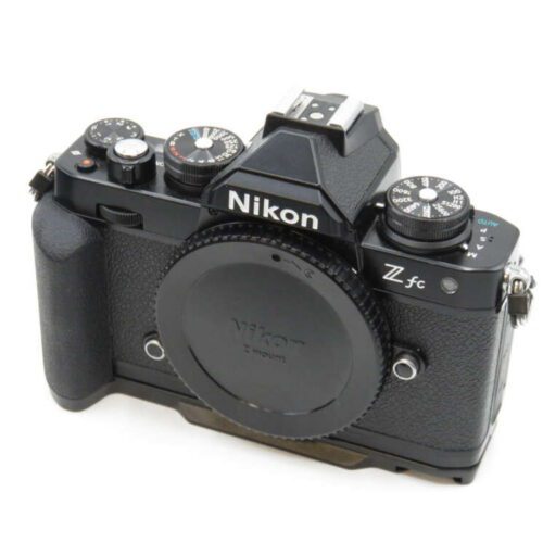 A black Nikon Z fc camera with various control dials and a textured grip, viewed from the top and slightly from the front.