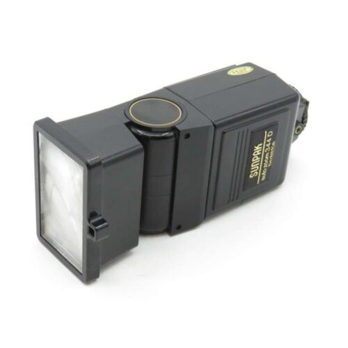 A vintage Sunpak auto zoom flash unit with a tilting head and control buttons, placed on a white surface.