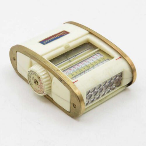 A vintage mechanical manual calculator with a brass frame, a white body, and a rotating dial featuring numbers and a ruler scale.