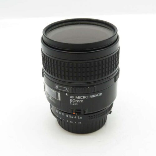 A black AF Micro Nikkor 60mm 1:2.8 camera lens standing upright on a plain white surface.