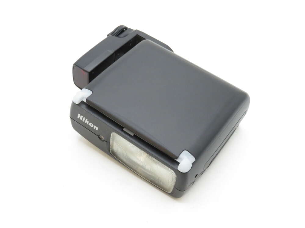 IMG_3595 A black Nikon speedlight flash unit with a foldable design and visible lens on the front.
