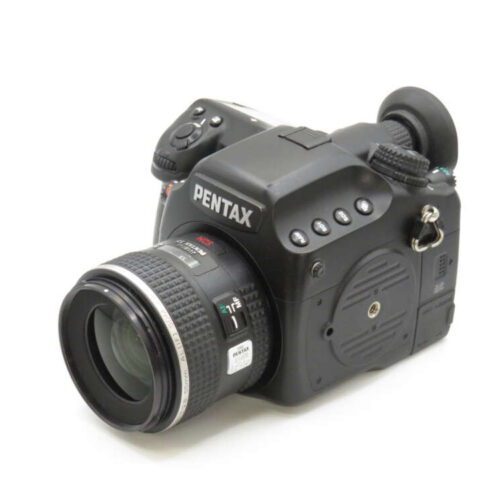 A black Pentax DSLR camera with a zoom lens, numerous buttons, and a viewfinder on a white background.