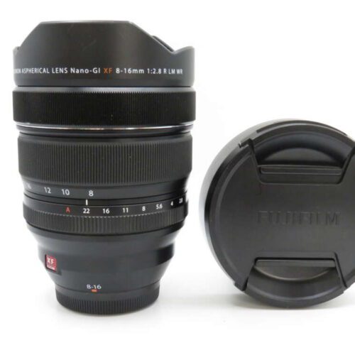 A Fujifilm XF 8-16mm f/2.8 R LM WR camera lens standing next to its lens cap.