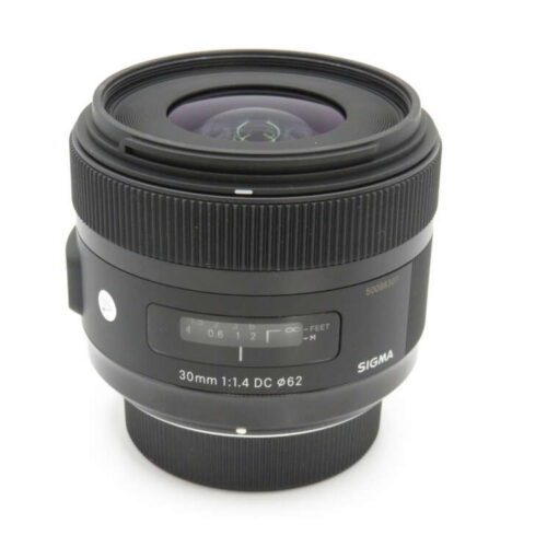 A Sigma 30mm f/1.4 DC lens with focus and distance scales visible near the base.