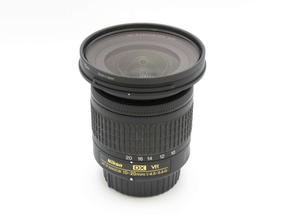 IMG_3665 A Nikon DX VR 10-20mm camera lens with detailed markings on a white background.