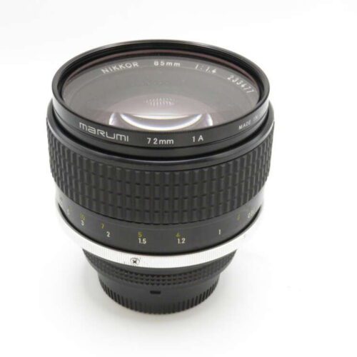 A Nikon 85mm camera lens with a textured focus ring and Marumi filter attached.