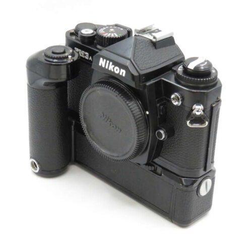 A black Nikon FE2 film camera with a vertical grip attachment, viewed slightly from the side.