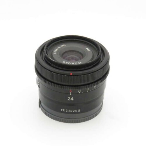 A black camera lens with markings "FE 2.8/24 G" and "24" on the focus ring, set against a white background.