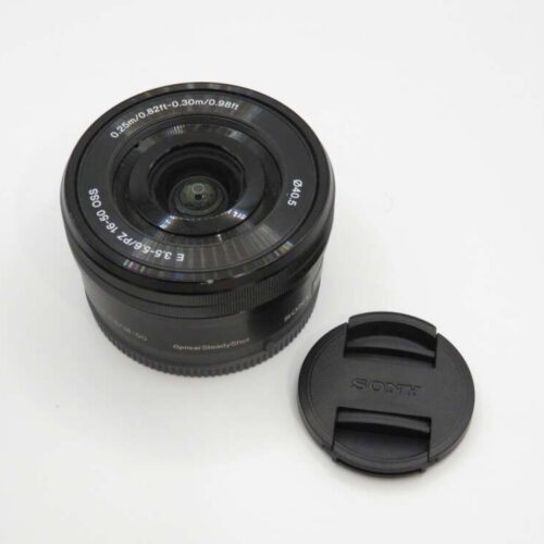 A black camera lens with a separate lens cap placed beside it on a white surface.
