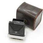 A vintage camera viewfinder with black textured panels and a lens, accompanied by a brown leather case.