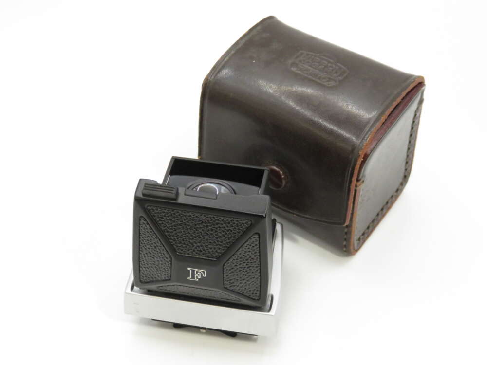 A vintage camera viewfinder with black textured panels and a lens, accompanied by a brown leather case.