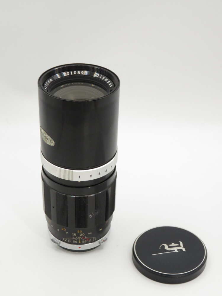 IMG_3827 A black vintage camera lens with a silver ring, featuring visible numbers and a detached lens cap with a logo next to it.