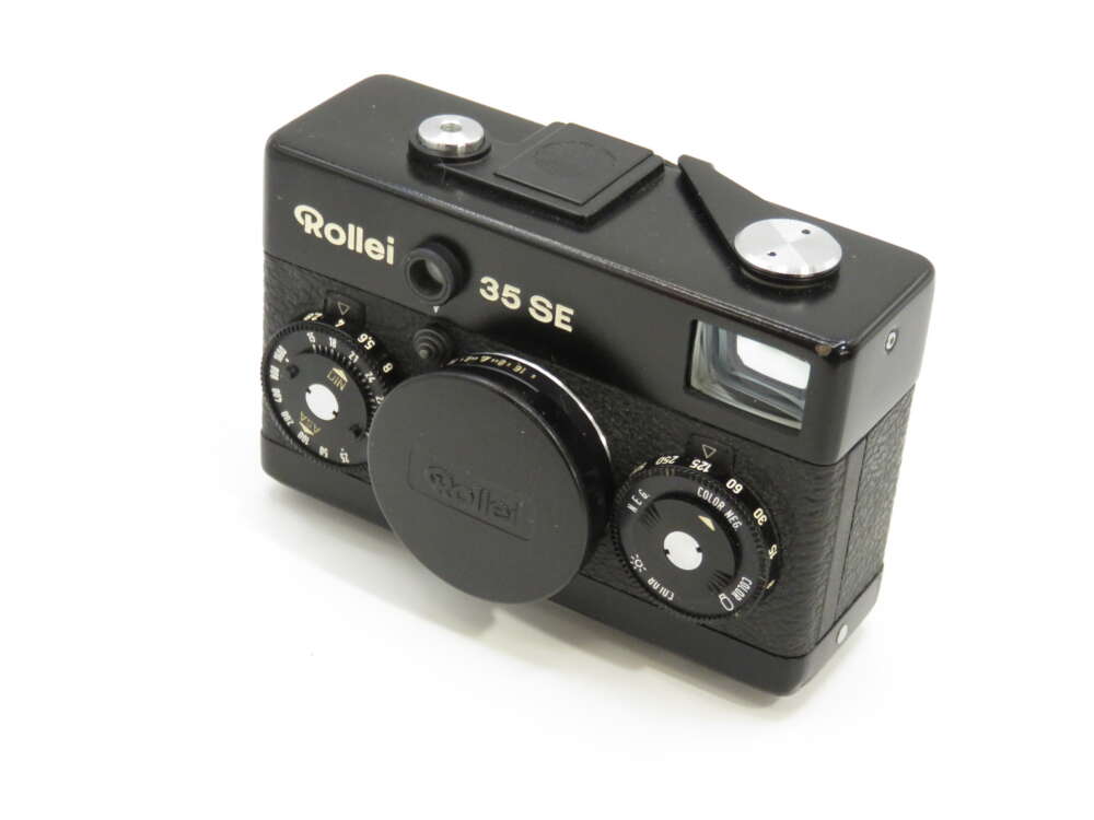 IMG_3868 A vintage Rollei 35 SE camera with a black body, lens cover, and various control dials visible.