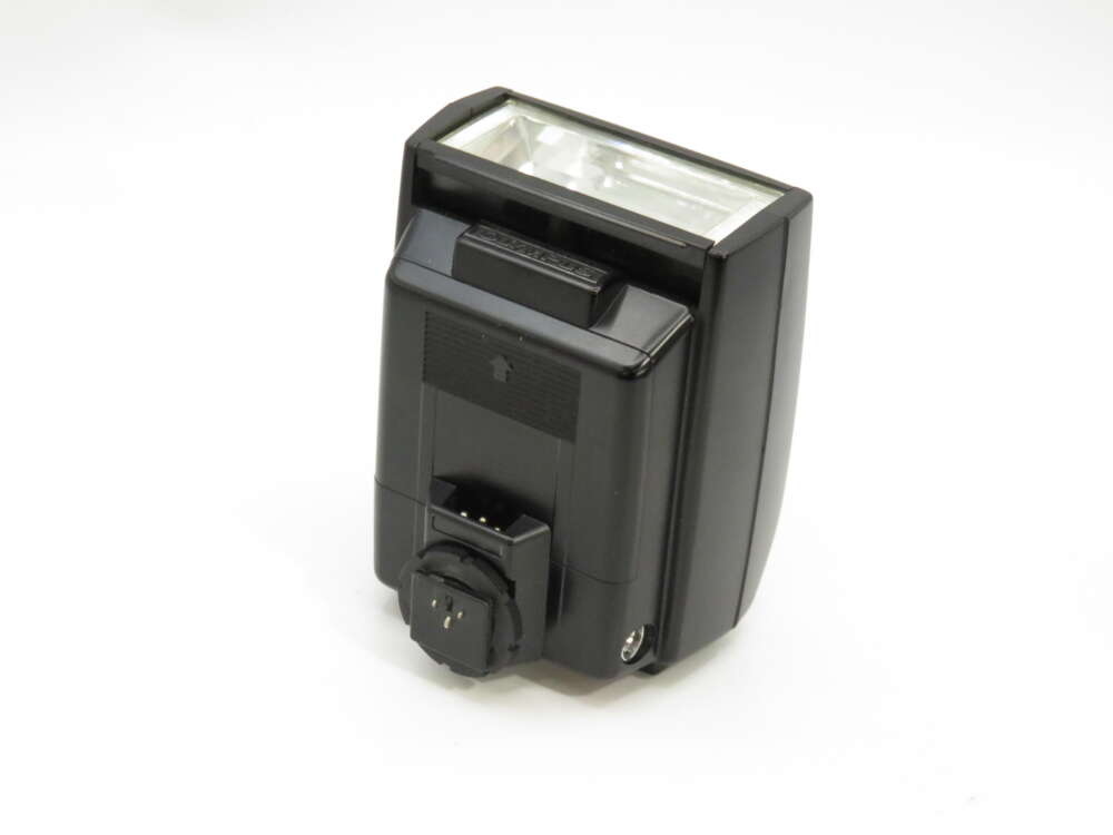 IMG_3877 Camera flash unit with a rectangular flash head, hot shoe mount, and control panel on the back, set against a plain background.