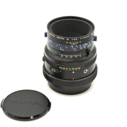 A Mamiya Macro lens with detailed markings and its protective lens cap placed beside it.