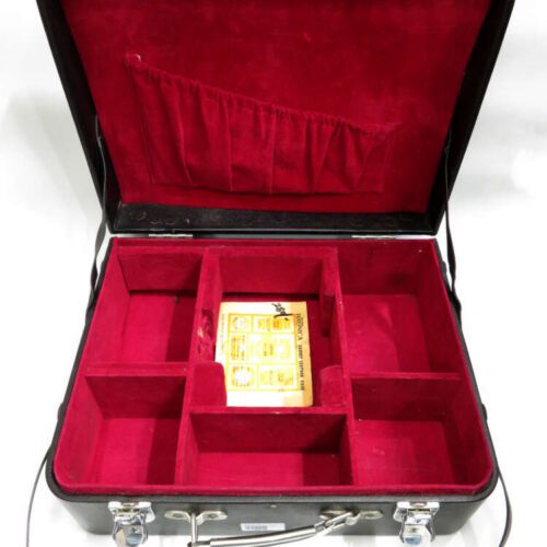 An open black case with red velvet lining, featuring multiple compartments and a small box in the centre section.
