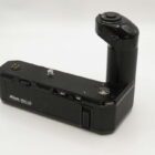 A Nikon MD-12 motor drive for cameras, featuring a grip and control buttons, set against a plain background.