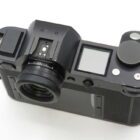 Black digital camera viewed from the top with a small LCD screen and several buttons.