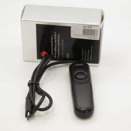 Remote control with a black casing and a cable next to a white box labeled "Leica."