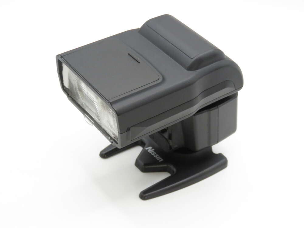 IMG_4008 A compact camera flash unit with dual flash heads, on a small black stand.
