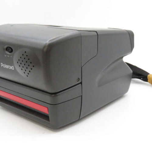 A vintage Polaroid instant camera with a dark grey body and a red film slot, featuring a carrying strap.