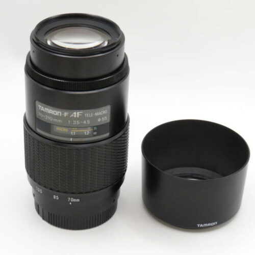 A Tamron F 4F tele-macro lens with a separate lens hood placed beside it.
