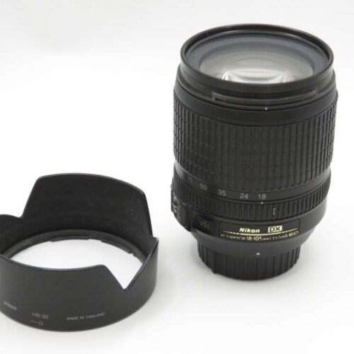 A Nikon camera lens and a detached lens hood on a white background.