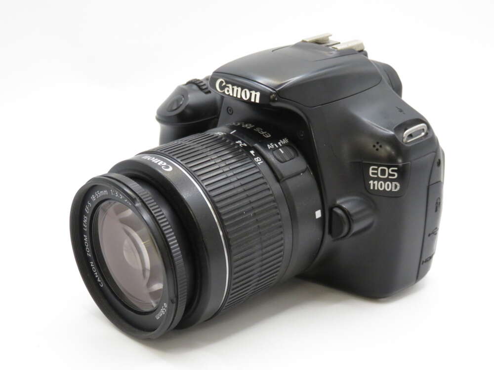 IMG_4187 A black Canon EOS 1100D DSLR camera with a lens attached, angled to show the lens and part of the body.